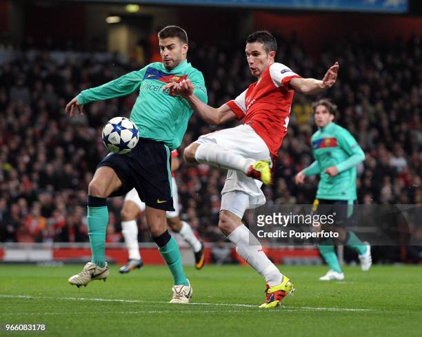 Robin van Persie of Arsenal and Gerard Pique of Barcelona battle for the ball during the UEFA Champions League round of 16 first leg match between...