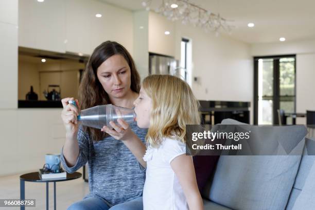 mother giving asthma treatment to asthmatic daughter - asthma inhaler child stock pictures, royalty-free photos & images