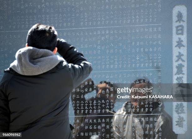 Relatives of the victims are looking for the name of the friend in the monumen during the second anniversary of the 2011 Tohoku earthquake and...