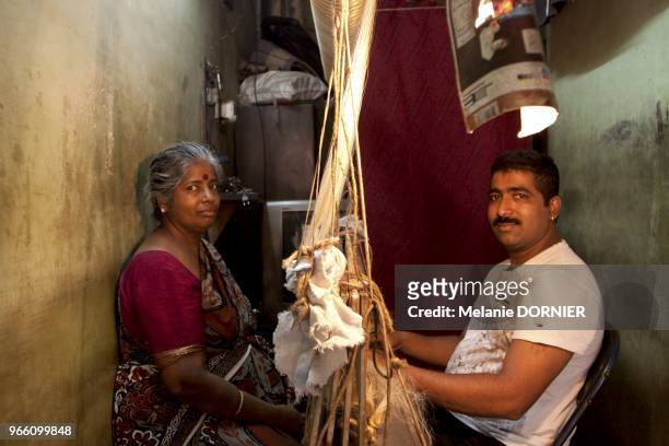 Bangalore dans un petit atelier en juin 2013, un fils et sa mere sont entrain de preparer un rouleau de metier a tisser. Les fils de soie doivent...