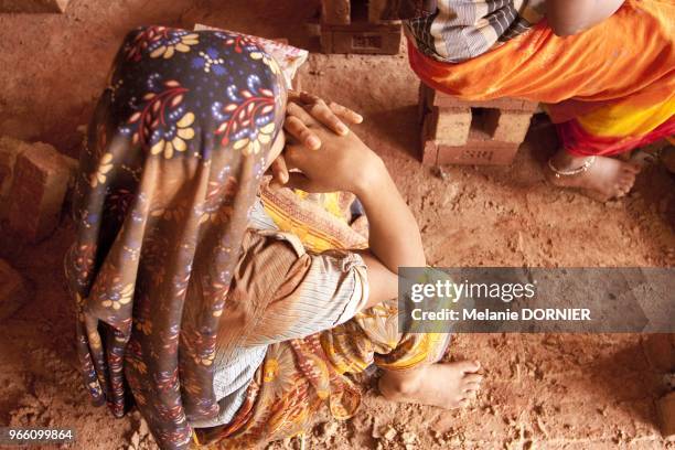 Vue d'une travailleuse migrante assise sur une brique pendant sa pose a Bangalore Mai 2013.