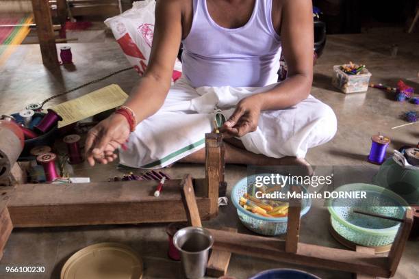 Bangalore a Yelanka en juin 2013, le proprietaire de l'atelier de metier a tisser manuel est assis par terre enroulant manuellement les navettes des...