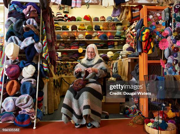 Senior female hat maker working on her hand crafts market stall.