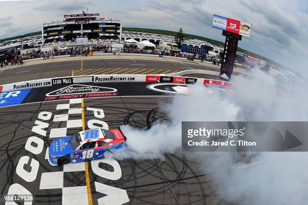 Kyle Busch, driver of the Comcast Salute to Service/Juniper Toyota, celebrates with a burnout after winning the NASCAR Xfinity Series Pocono Green...