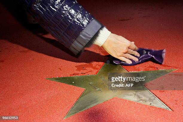 An organiser uses her glove to clean the newly unveiled star bearing the name of German actress Marlene Dietrich at Potsdamer platz on the sidelines...
