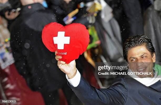 Indian actor Shah Rukh Khan holds up a heart with the Swiss flag on it to fans as he arrives for a photocall for his film My Name is Khan during the...