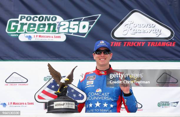 Kyle Busch, driver of the Comcast Salute to Service/Juniper Toyota, poses for a photo with the trophy in Victory Lane after winning the NASCAR...