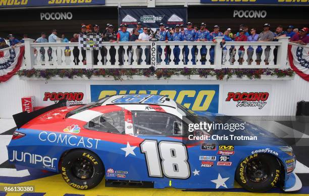 Kyle Busch, driver of the Comcast Salute to Service/Juniper Toyota, poses for a photo with the trophy in Victory Lane after winning the NASCAR...