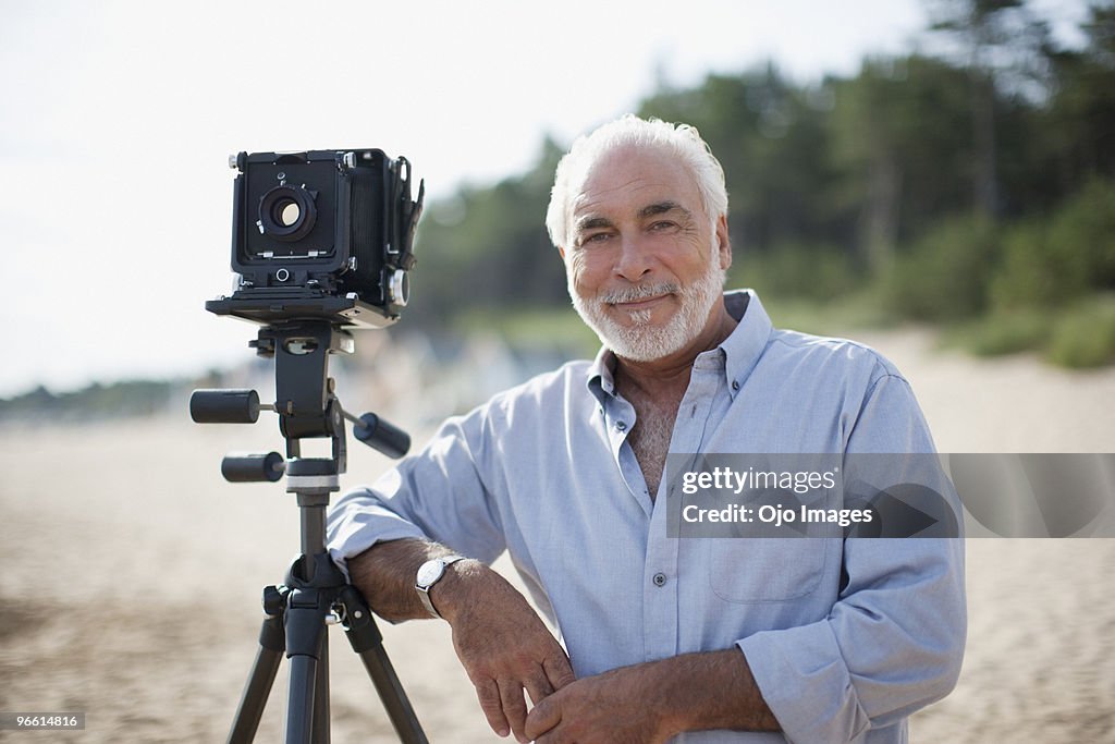 Man leaning on old-fashioned camera at beach