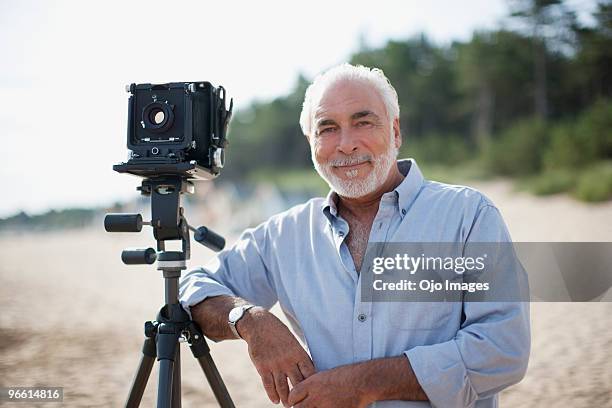 man leaning on old-fashioned camera at beach - man photographer stock pictures, royalty-free photos & images