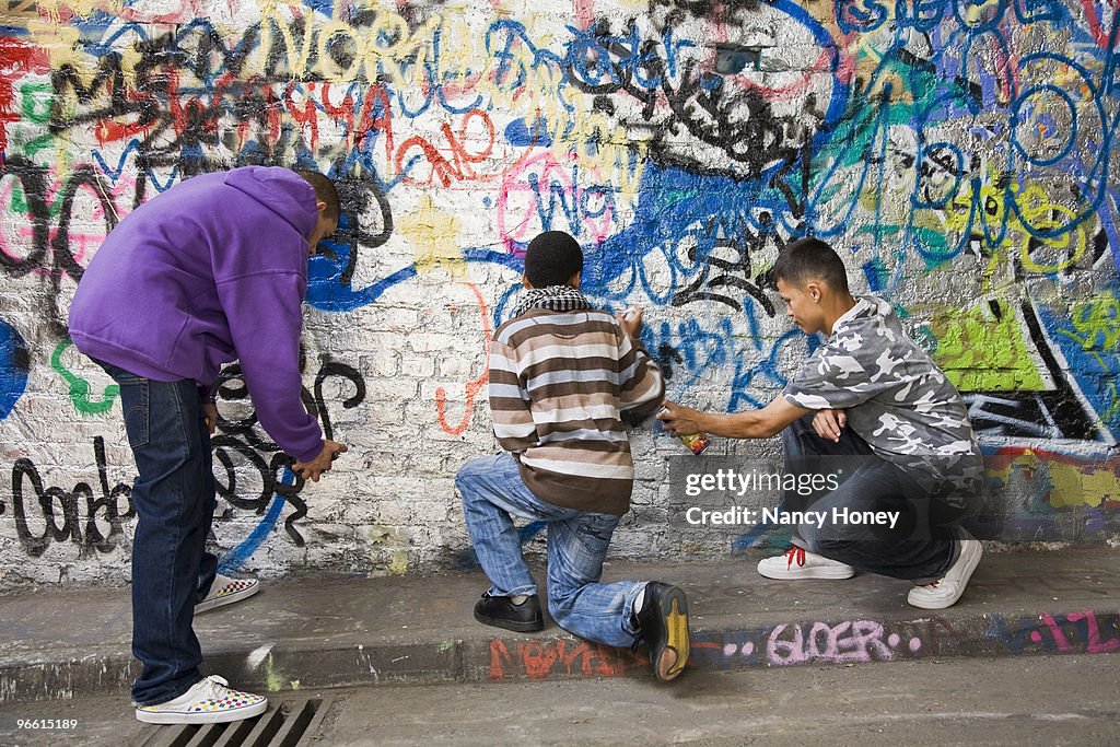 Teenage gang doing graffiti on a wall