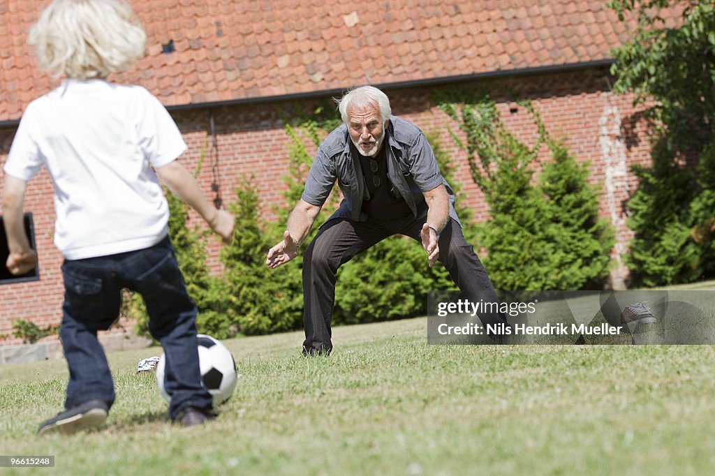 Grandfather and child playing football