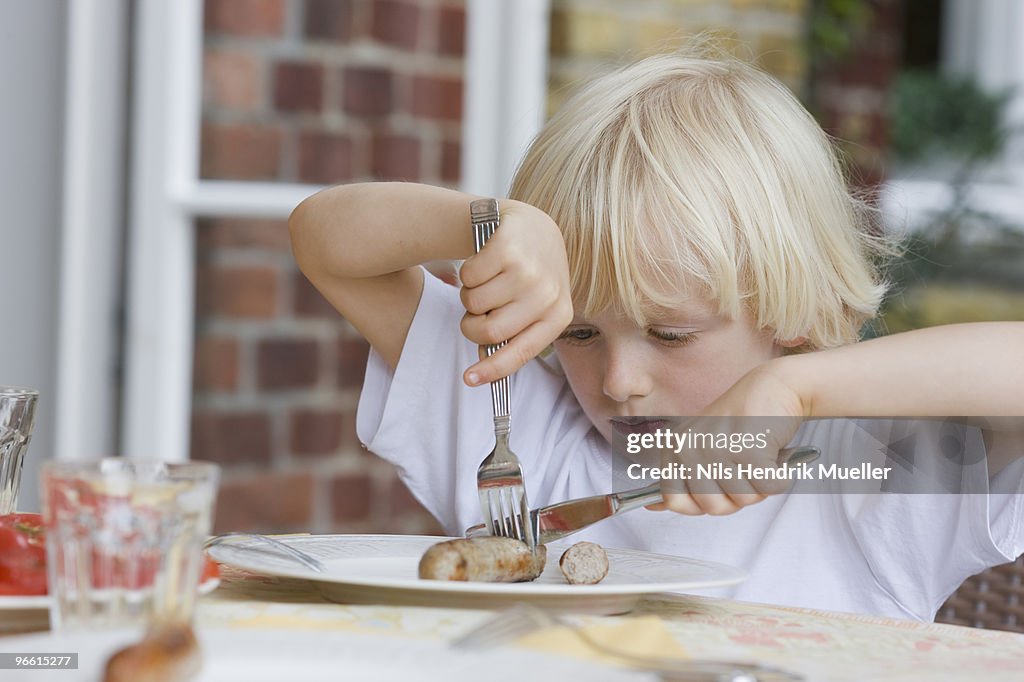 Boy eating with knife and fork