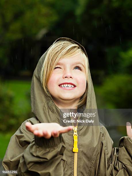 girl holding her hand out to catch rain - caught in rain stock pictures, royalty-free photos & images