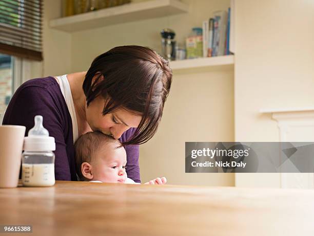 mother kissing her baby in the kitchen - mother son milk imagens e fotografias de stock