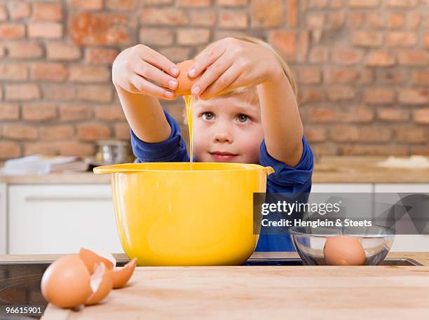 boy adding eggs to bowl - genderblend2015 stock pictures, royalty-free photos & images