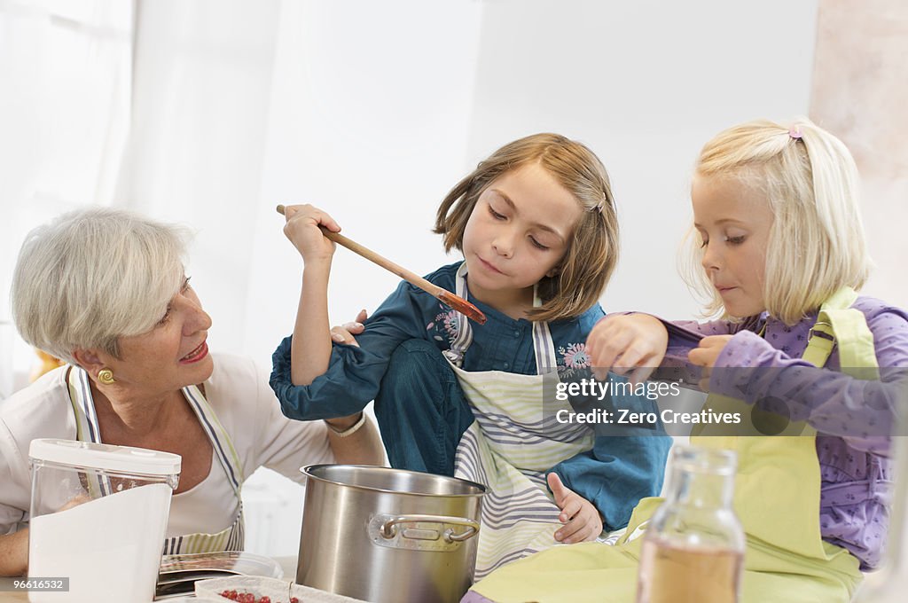 Girls with grandmother cooking jam