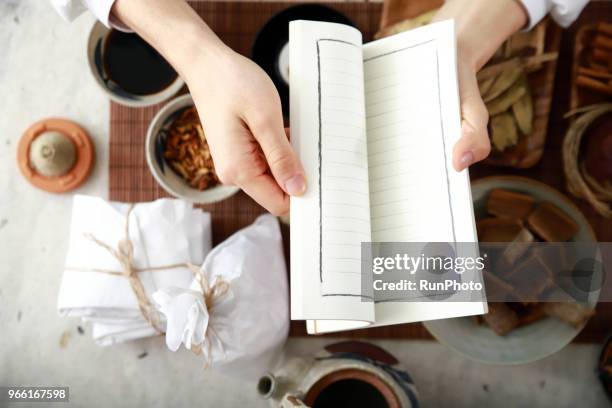 traditional chinese physician with book and herbal medicine - angelica hale stock pictures, royalty-free photos & images