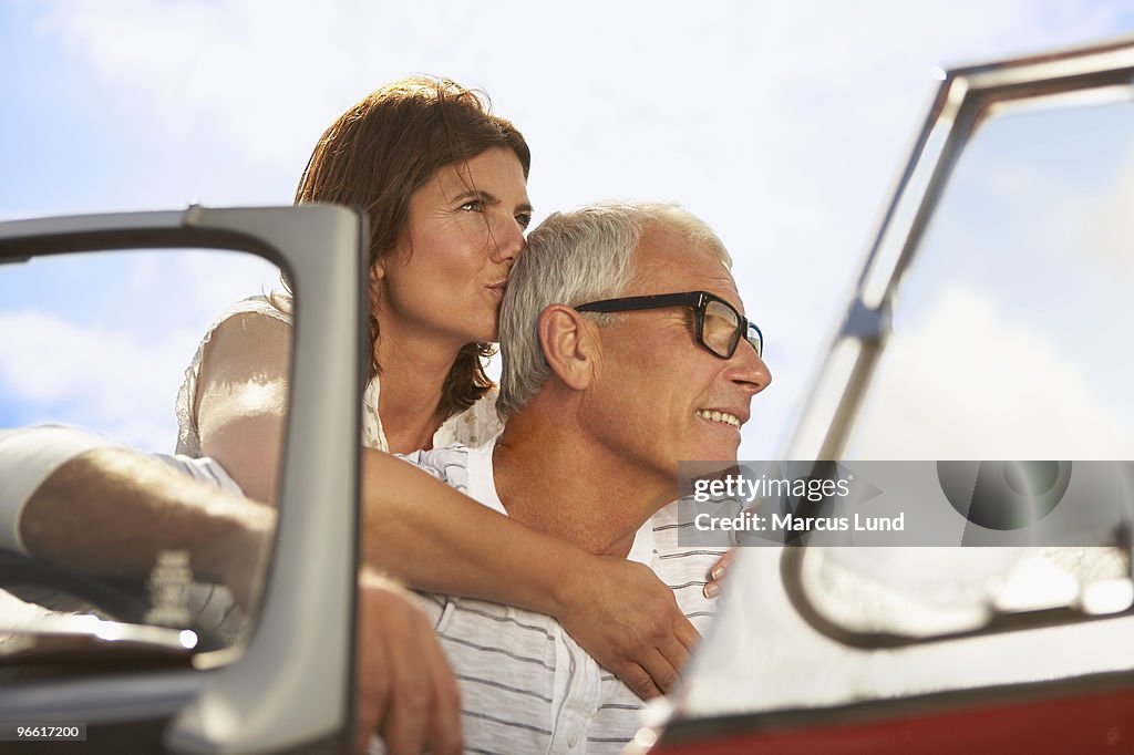 Senior couple embracing in sports car