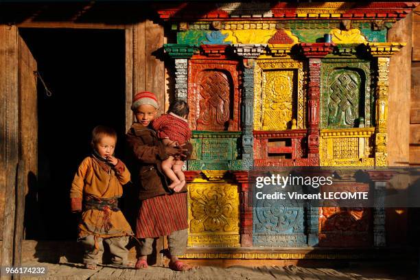 Enfants népalais de la communauté Tamang sur le balcon de leur maison en bois du village de Gatlang, au Népal, le 19 avril 2012 - L?architecture de...