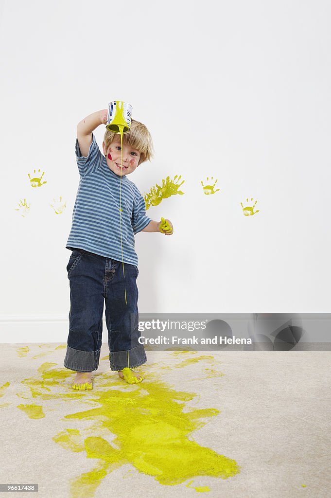 Toddler boy pouring paint onto carpet