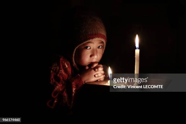Enfant de la communauté Tamang s?éclairant à la bougie dans sa maison, à la tombée de la nuit, dans le hameau de Naghtali Ghyang, au Népal, le 22...