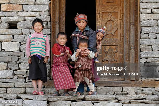 Enfants népalais de la communauté Tamang devant un bâtiment de leur village de Gatlang , au Népal, le 20 avril 2012 - Le garçon au centre porte un...