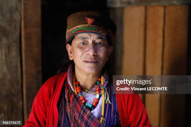 Femme népalaise de la communauté Tamang portant un chapeau Tamang et des colliers avec des pierres de turquoise, dans sa maison, dans le hameau de...