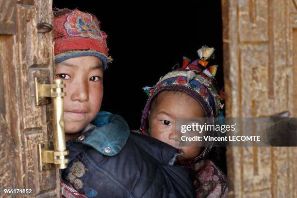 Deux enfants népalais de la communauté Tamang posant dans l?embrasure de la porte d?un bâtiment en pierres dans le village de Gatlang, au Népal, le...