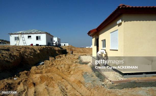 Worker spreads stone around the outside of a one of the finished pre-fabricated homes as a new shipment of 12 of the pre-fabricated homes intended to...