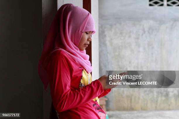 Adolescente indonésienne voilée utilisant son téléphone portable à la récréation à l'école de Basca à Painan, au sud de l?île de Sumatra, en...