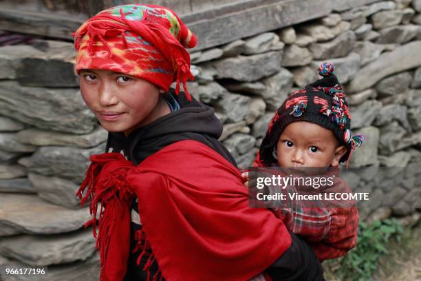 Jeune mère népalaise, de la communauté Tamang , portant son petit garçon dans son dos, dans le village de Gatlang , au Népal, le 18 avril 2012.