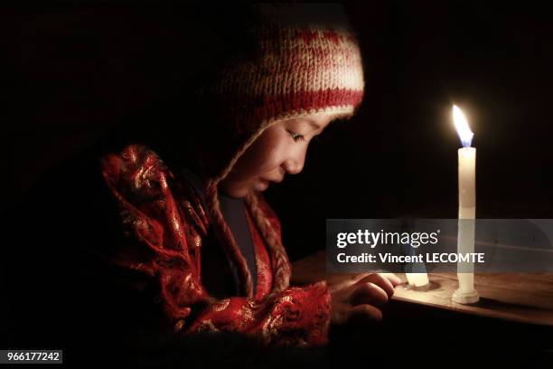 Portrait en clair-obscur d?un enfant de la communauté Tamang éclairé à la bougie, dans sa maison, à la tombée de la nuit, dans le hameau de Naghtali...