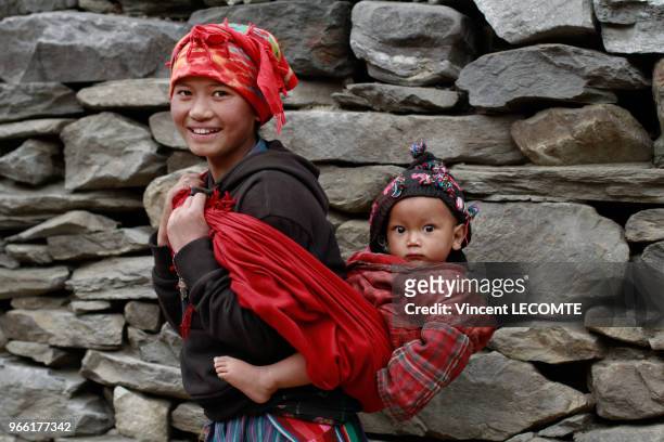 Jeune mère népalaise, de la communauté Tamang , portant son petit garçon dans son dos, dans le village de Gatlang , au Népal, le 18 avril 2012.