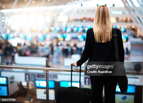 giovane donna che si affaccia sull'atrio del check-in in aeroporto - businesswoman blond looking left foto e immagini stock