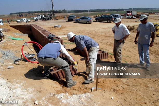 Workers place masonary bricks around the site for one of the new homes as a new shipment of 12 of the pre-fabricated homes intended to serve as...
