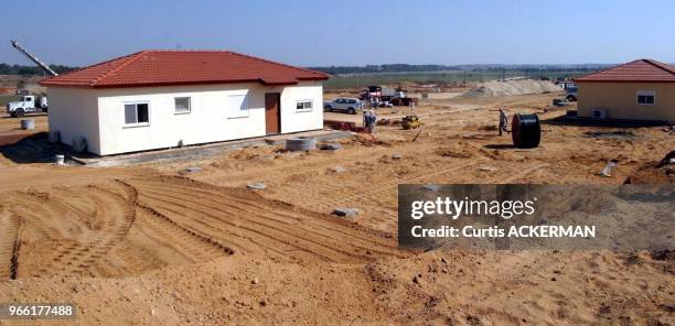 Workers put the finishing touches on one of the finished pre-fabricated homes as a new shipment of 12 of the pre-fabricated homes intended to serve...