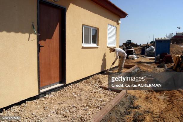 Worker spreads stone around the outside of a one of the finished pre-fabricated homes as a new shipment of 12 of the pre-fabricated homes intended to...