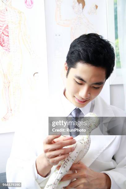 oriental medical doctor applying needles on acupuncture moel - anatomista fotografías e imágenes de stock