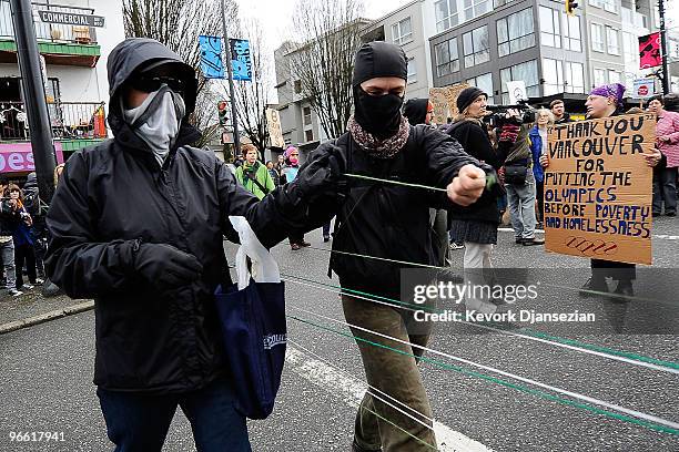 Protesters tie string across the street to demonstrate during the Olympic torch relay on February 12, 2010 in Vancouver, Canada. The torch relay had...