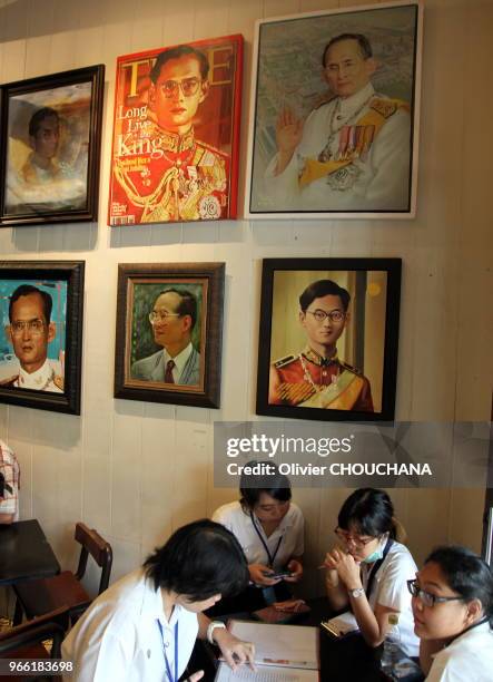 Jeunes thailandais prennant un verre dans un petit restaurant et café thailandais entièrement recouvert des portraits du roi de Thailande le 17...