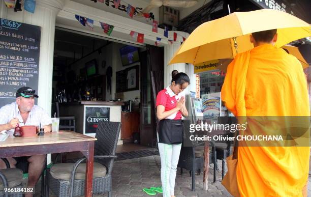 Des moines cambodgiens benissent une serveuse devant un restaurant dans les rues de la capitale le 23 Fevrier 2017, Phnom Penh Cambodge.