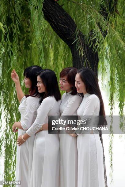 Jeunes vietnamiennes posant en Ao dai, la robe traditionnelle du Vietnam, au bord du lac de Hoan kiem le 15 novembre 2016, Hanoi Vietnam.