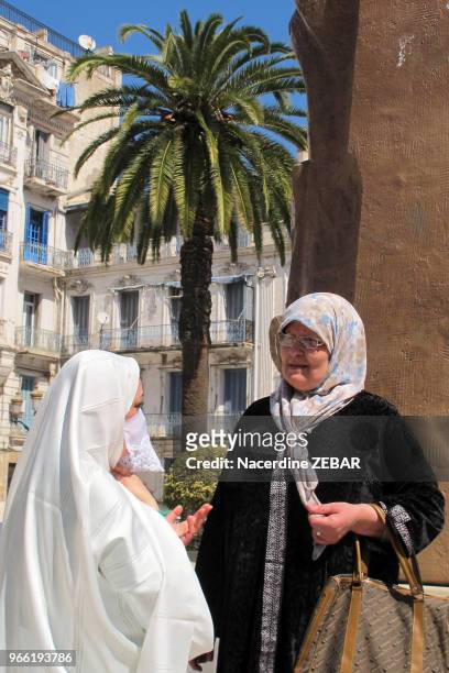 Deux femmes algéroises dont une porte une tenue traditionnelle le 'haik', étoffe symbole de pureté, discutant dans la rue, le 21 mars 2013, à Alger,...
