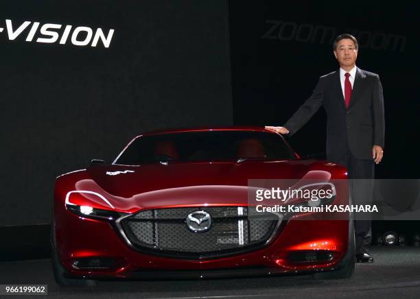 Masamichi Kogai, president and CEO of Mazda, stands beside new sports concept car " RX-VISION" during the Tokyo Motor Show 2015 press preview day in...