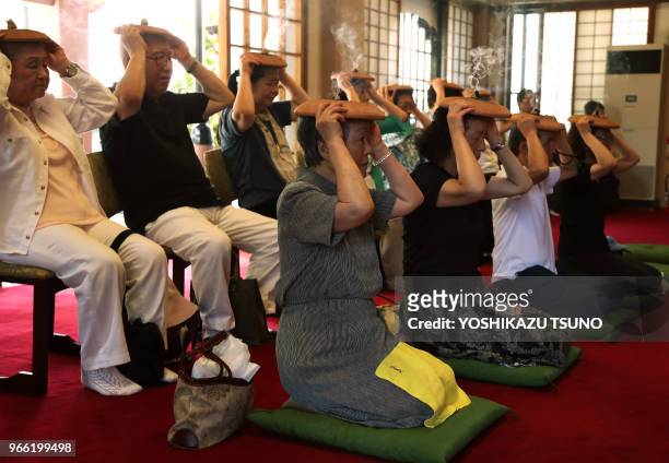 Bouddhistes brûlant le moxa sur des plateaux de poterie sur leurs têtes, prient pour avoir une bonne santé lors d'un rituel d'été traditionnel au...