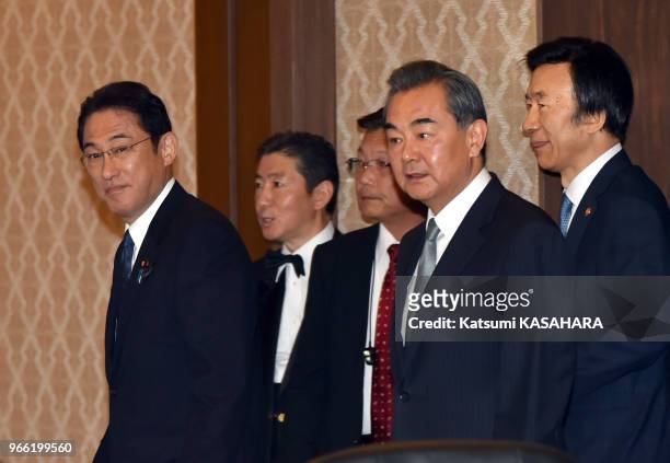Japanese Foreign Minister Fumio Kishida, left, escortes Chinese Foreign Minister Wang Yi, center, South Korean Foreign Minister Yun Byung-se, right,...
