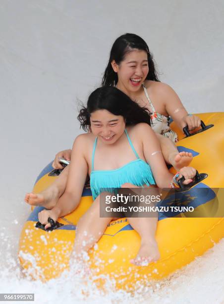 Two girls ride a rubber boat sliding into a swimming pool at the Toshimaen amusement park in Tokyo on July 24, 2016. Some 14,000 people visited the...