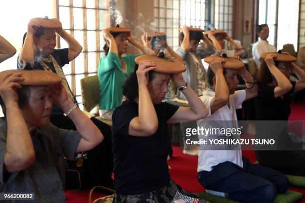Bouddhistes brûlant le moxa sur des plateaux de poterie sur leurs têtes, prient pour avoir une bonne santé lors d'un rituel d'été traditionnel au...
