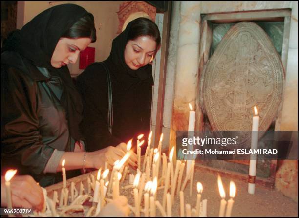 Two Christian girls light candels after general praying for Christmas time in St. Sarkis church in Tehran.